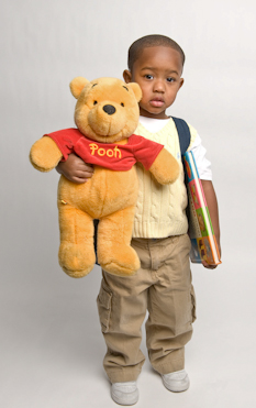 男孩拿着背包，书和小熊维尼毛绒玩具