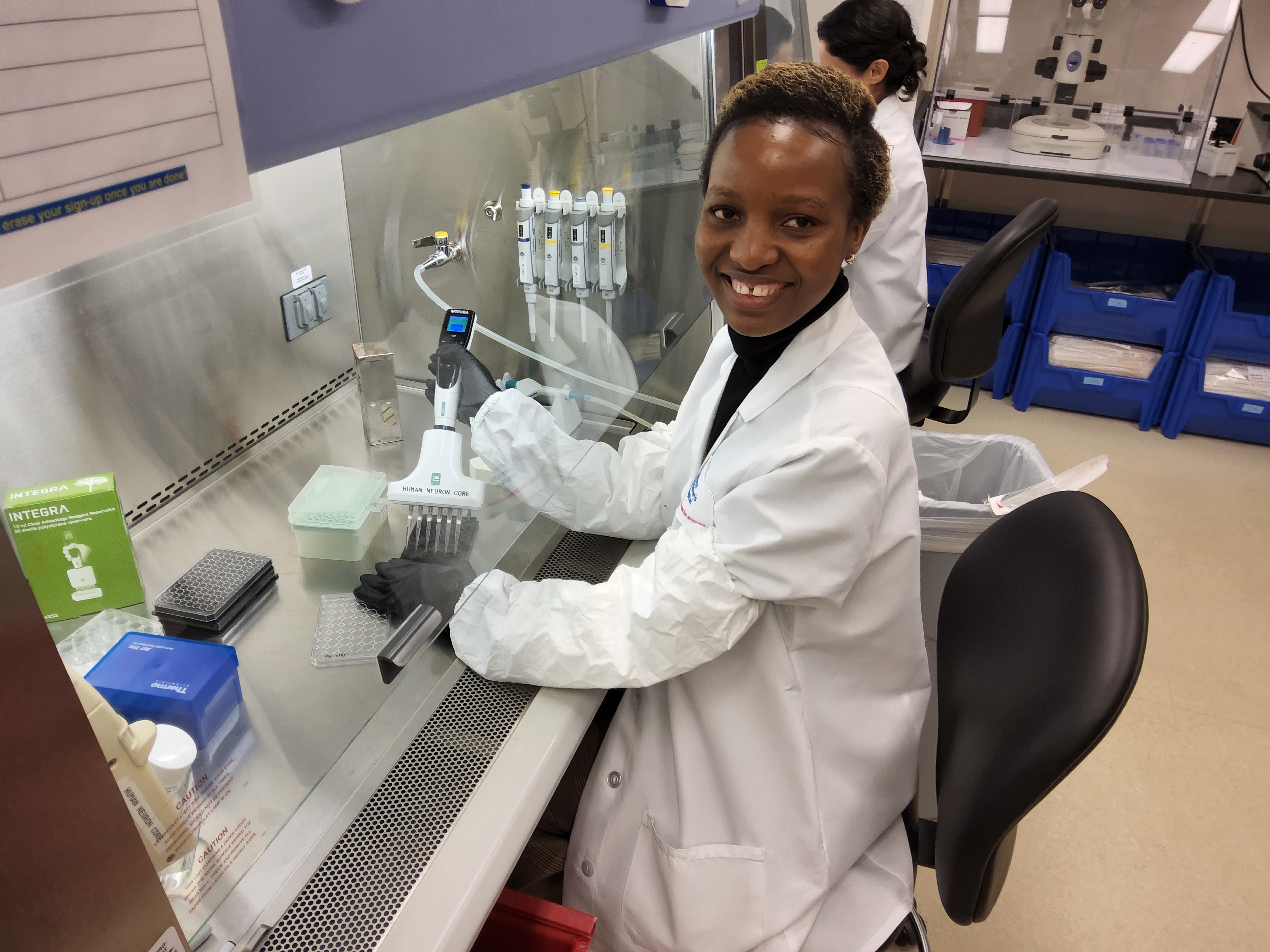 一名身穿波士顿儿童医院白大褂的黑人妇女在实验室工作站为移液管注水。